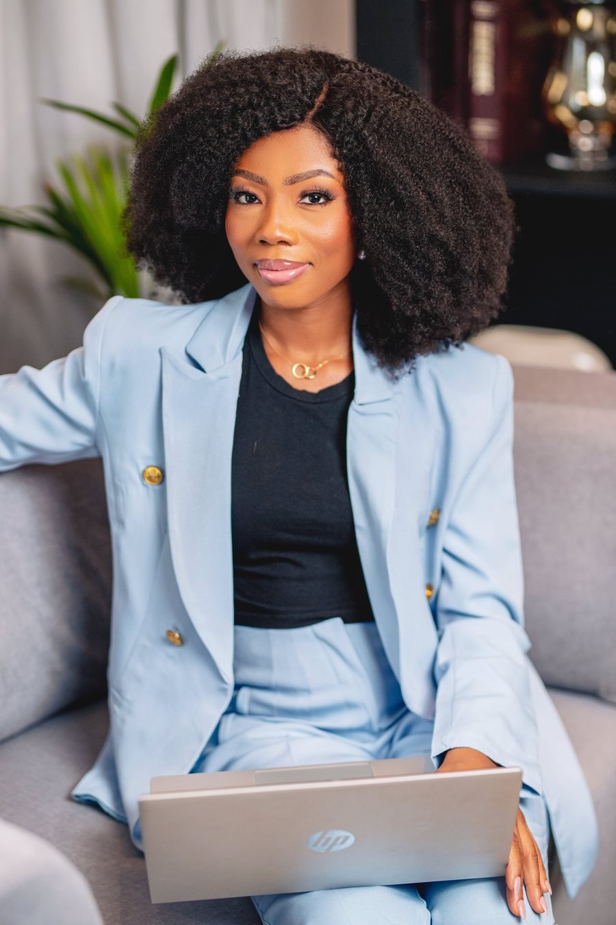 Yayra Doulce seated in a bright professional workspace with a calm confident expression and a laptop nearby
